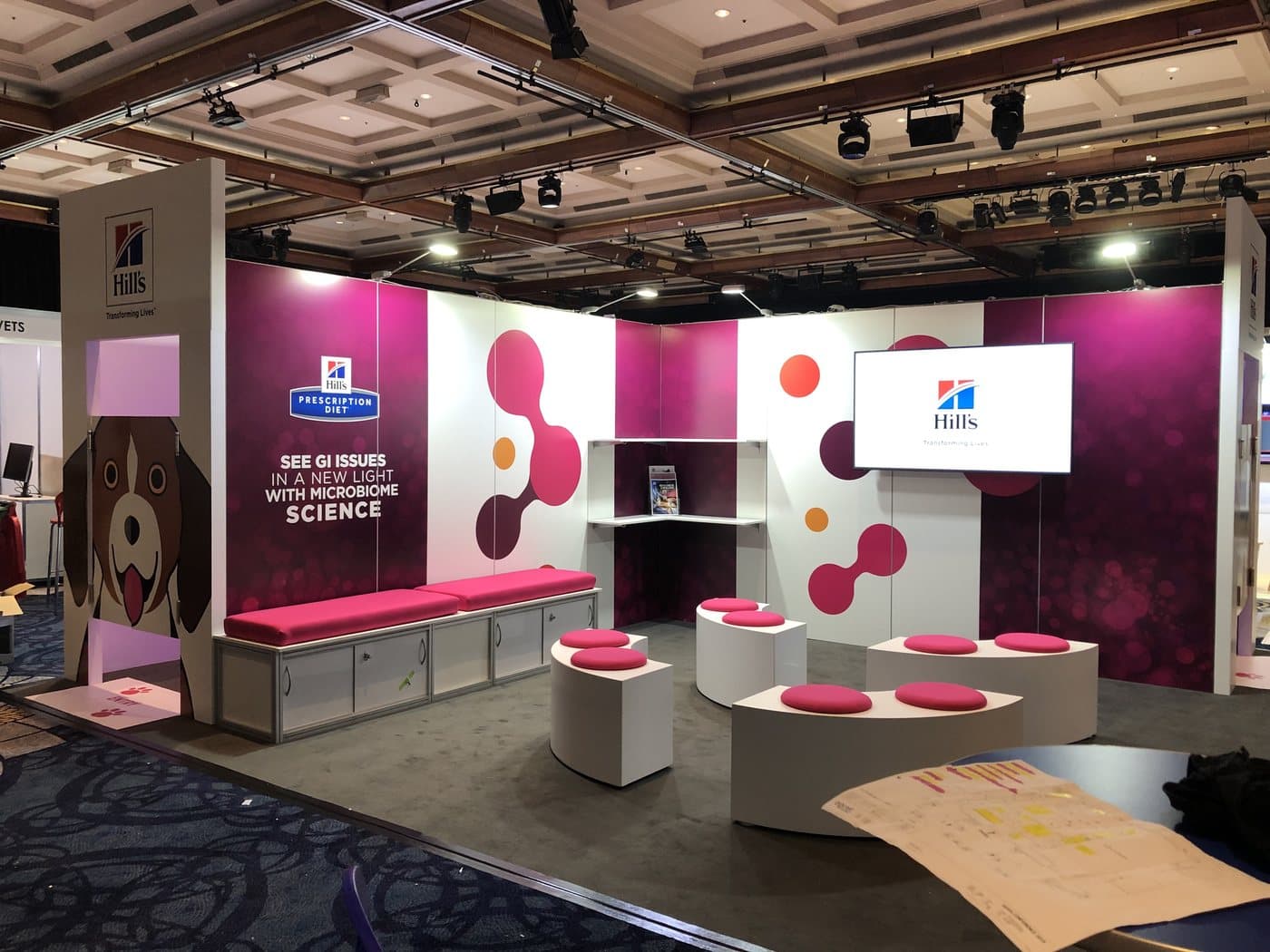 Exhibition stand with pink printed walls and display plinths